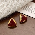 Close-up of geometric triangle earrings with red enamel on a warm wooden surface - Ancorra Red