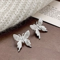 Détail de boucles d'oreilles papillon en argent avec texture brossée et zircon sur bois - Boucles d'Oreilles Papillon Zircon Argenté