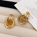 Nahaufnahme der goldenen mehrschichtigen Knotenohrringe auf edlem Schmuckkästchen - Gold