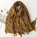 Sciarpa gialla con stampa leopardata e nappe stesa su uno sfondo bianco pulito - Stile Leopardato Giallo Zenzero (SL2305-002)