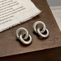 Detailopname van matte geborstelde zilveren dubbele ringen op vintage stoffen basis - Koffie Goud Dubbele Ring