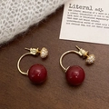 Pendientes de aro en C dorados con perlas rojas y circón sobre fondo retro texturizado - Pendientes de Perlas Rojas