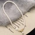 Dettaglio collana di perle con ciondolo a fiore bianco e chiusura OT dorata su tessuto - Collana
