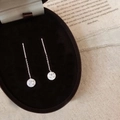 Primer plano de pendientes de hilo de plata con circonitas sobre terciopelo negro - Plateado