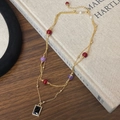Dettaglio di una collana dorata a strati con pendente in pietra nera e perle colorate - Stile Pietra Preziosa Nera a Doppio Strato (B-536)