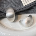 Close-up of matte silver brushed C-shape earrings on a white ceramic plate - Brushed Silver