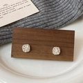 Macro-opname van zilveren geometrische oorbellen met steentjes op houten display - Zilver