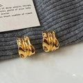 Boucles d'oreilles dorées en forme de C avec texture de lave irrégulière et style minimaliste - Doré