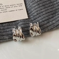 Gros plan de boucles d'oreilles argentées à vagues avec texture métal liquide - Argenté