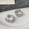 Silver quilted pattern hoop earrings in a polished metallic finish on a white plate - Silver