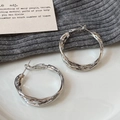 Nahaufnahme silberner Creolen mit gedrehter Webstruktur auf grauem Strickstoff - Gedrehter Silberstil (A-1211-Silber)
