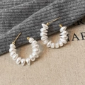 Eleganti orecchini a cerchio a C con perle e dettagli dorati su sfondo minimalista - Orecchini a Lobo a Forma di C con Perle