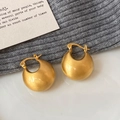 Close-up van gouden dikke oorringen met een geborstelde matte textuur op zachte stof - Mat Geborsteld Goud