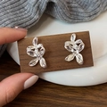 Silver flower stud earrings with layered metal petals displayed on dark wooden board - Silver