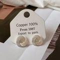 Close-up of twisted layered silver earrings on display card with intricate texture - Silver