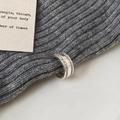 Dettaglio macro di un orecchino ear cuff argento con zirconi su maglia grigia - Argento