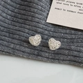 Detailed macro view of heart-shaped hollow woven mesh earrings in silver metal finish - Heart Hollow Woven Stud Earrings / Silver
