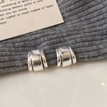 Makroaufnahme silberner Metallohrringe mit Hammerschlag-Textur im minimalistischen Design - Silber