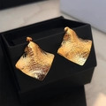 Boucles d'oreilles carrées dorées à texture géométrique sur une boîte à bijoux noire - Doré