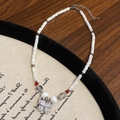 Vue détaillée d'un collier papillon avec strass brillants et perles blanches sur présentoir - Collier papillon
