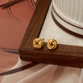 Close-up of vintage gold twisted knot stud earrings with a matte textured finish - Gold