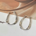 Vista macro de pendientes en U con diseño trenzado de plata pulida sobre fondo - Plateado