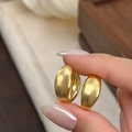 Primer plano de pendientes de aro dorados en metal cepillado con elegante acabado mate fino - Dorado