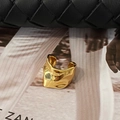 Macro detail of gold-plated fluid lava textured ear cuff on black woven leather base - Gold