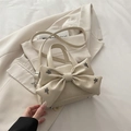 Elegante beige Handtasche mit Schleife, Sternennieten und Riemen auf cremefarbenem Blazer - Weiß