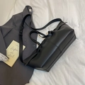 Minimalistische schwarze Tragetasche mit Falten und verstellbarem Gurt auf Bett - Schwarz