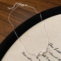 Dettaglio di collana minimalista in argento con tre perle bianche su tela vintage - Stile Perla a Catena Sottile Argentata / Bianco