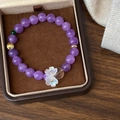 Close-up of amethyst beaded bracelet with white flower charms in a luxury jewelry box - Purple