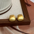 Dettaglio macro di orecchini trapezoidali dorati con finitura satinata - Stile Trapezio Spazzolato / Oro