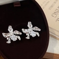 Detailed view of silver orchid flower earrings with a pear-cut zircon in a velvet jewelry box - Silver
