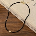 Detailansicht der schwarzen Perlenkette mit goldenem Mondanhänger auf einem Buch - Goldener Halbmond-Stil
