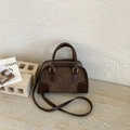Retro matte brown handbag with top handle and crossbody strap on stone surface - Brown