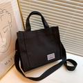 Minimalist black canvas tote bag with adjustable shoulder strap and woven label - Black