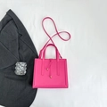 Detail of rose pink faux leather handbag with tassel knot and gold hardware on white fabric - Rose Red