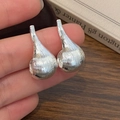 Macro shot of silver teardrop earrings with vertical brushed texture detail - Silver Stud Earrings