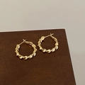 Detail of gold-plated twisted hoop earrings with unique metallic ripple texture on wood - Pleated 3D Twist Style (A-1209)
