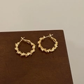 Detail of gold hoop earrings with twisted leaf texture on a wooden pedestal base - Twisted 3D Texture Style (A-1201)