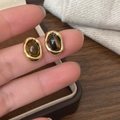 Gros plan de boucles d'oreilles dorées irrégulières avec pierres oeil de tigre - Or (Oeil de Tigre)