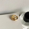 Close-up of 18K gold wave ring featuring a layered textured design and adjustable opening - Gold