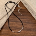 Dettaglio di un girocollo di perle nere con perle d'argento su sfondo di libro vintage - Collana Cucita Argento e Nero