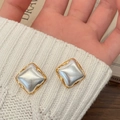 Close-up of square gold-plated earrings with pearlescent center on white knit fabric - Brushed Two-tone Square