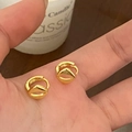 Détail de boucles d'oreilles dorées géométriques minimalistes tenues à la main - Doré