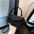 Bolso cuadrado negro trenzado con asa de nudo y detalles dorados llevado en la mano - Negro