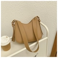 Minimalist camel saddle shoulder bag with wide strap and golden buckles on a white shelf - Khaki