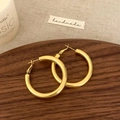 Detailed view of chunky polished gold hoop earrings on a vintage wooden tray - Gold 4cm Earrings