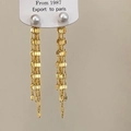 Vista macro de pendientes largos de borla dorada con perlas blancas y cadenas - Pendientes de Botón con Borla Dorada